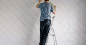 Adult man painting wall indoors during a home renovation project.